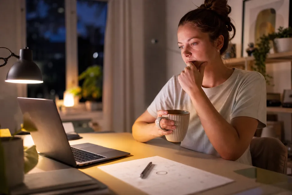A woman at her desk in the evening with a renewal date circled on a paper calendar